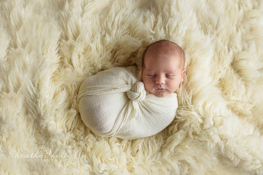 baby boy wrapped snug on flokati rug