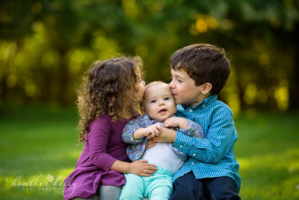 sibling photography big sister and big brother kissing little sister