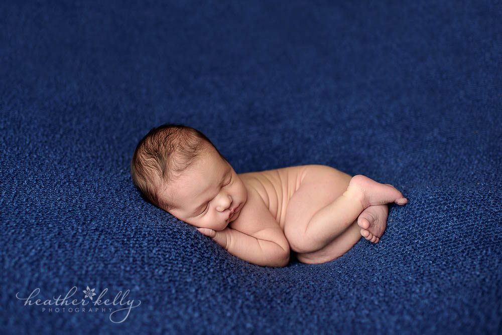 newborn photography photo of cute baby boy on navy backdrop snuggle pose fairfield newborn ct photographer