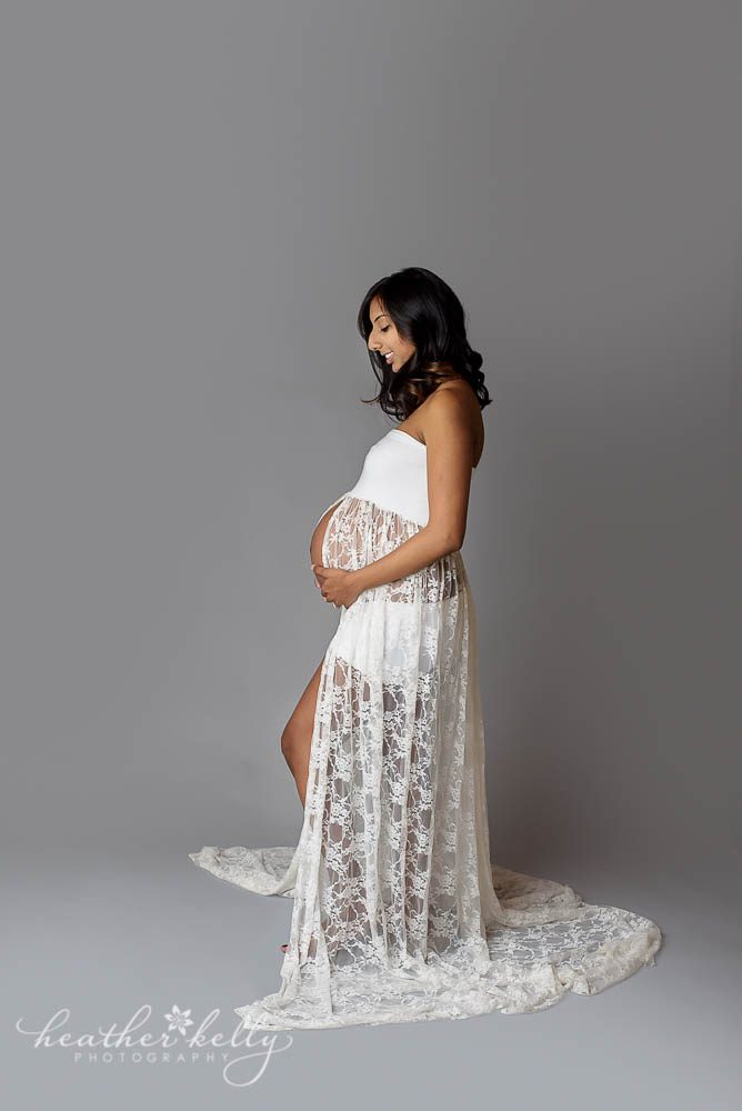 maternity photos of mom looking at belly in white gown
