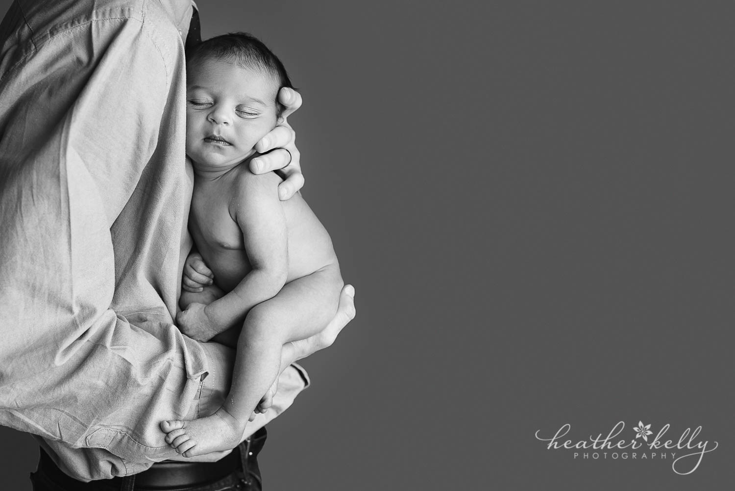 dad and newborn photo. Dad holding newborn boy to his chest. 