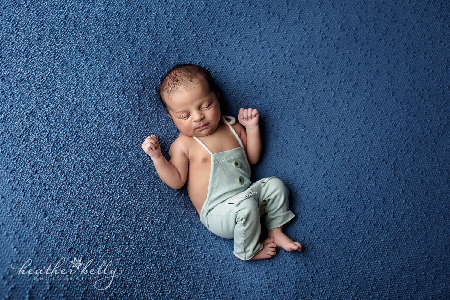 newborn boy on blue backdrop in adorable light blue romper photo. Newborn photography CT. 