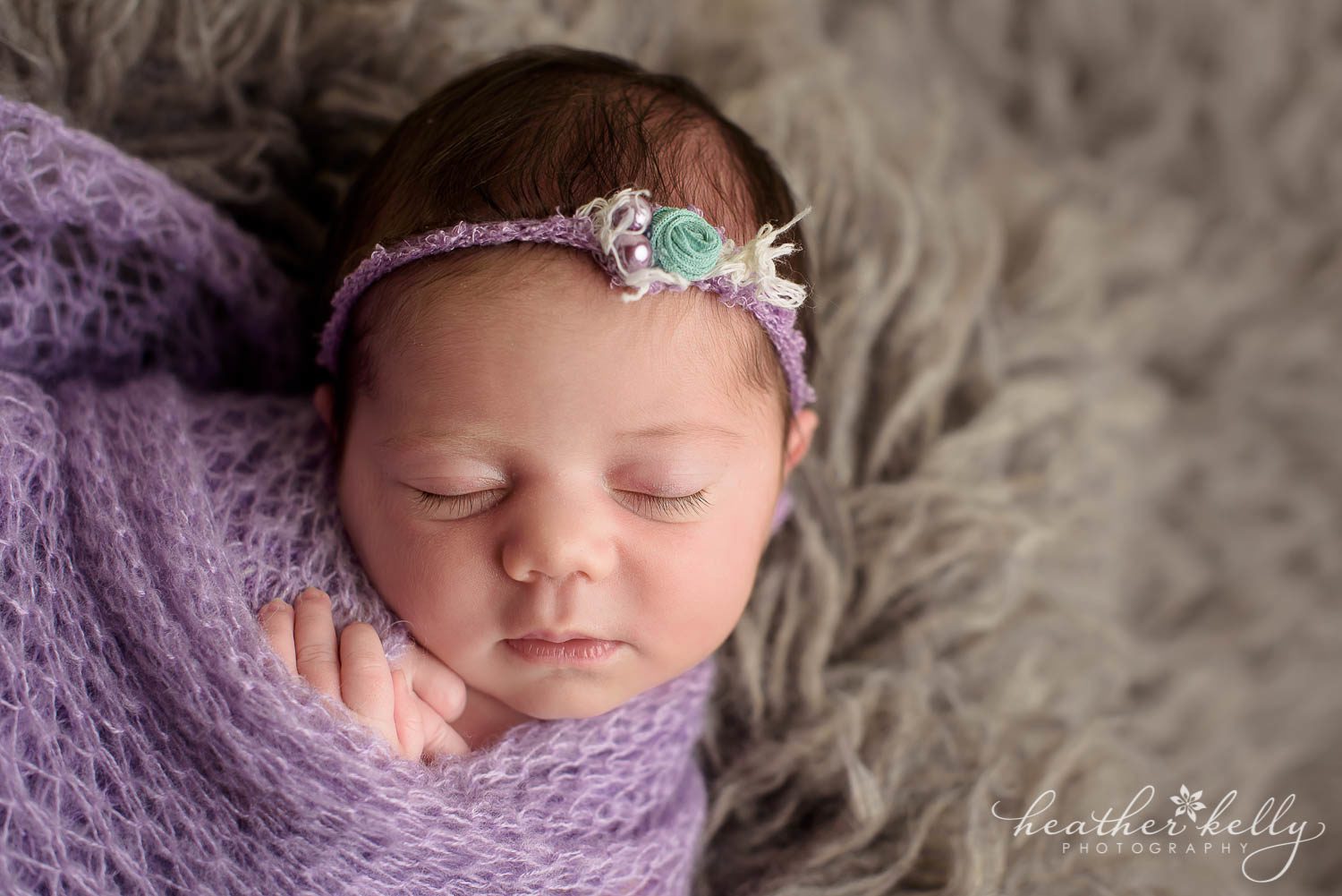 newborn girl close up image. She's wrapped in lavender wrap with hands showing on gray rug. Weston ct newborn photography