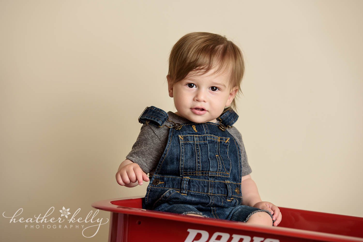 cute one year old wearing overalls in radio flyer wagon photo. little red wagon cake smash