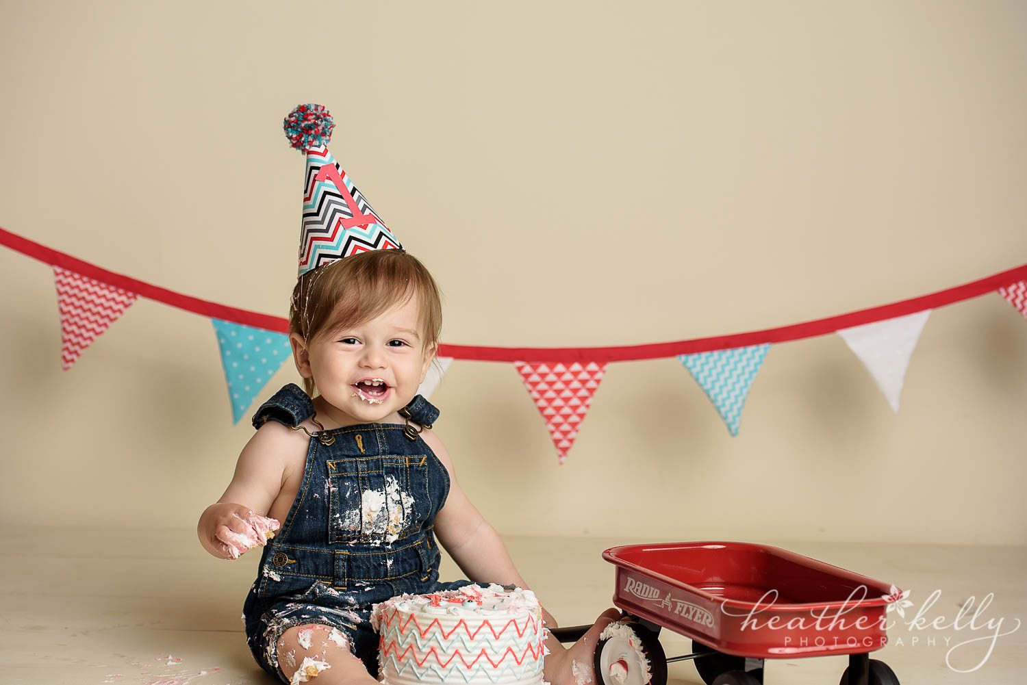smiling boy with little red wagon cake smash