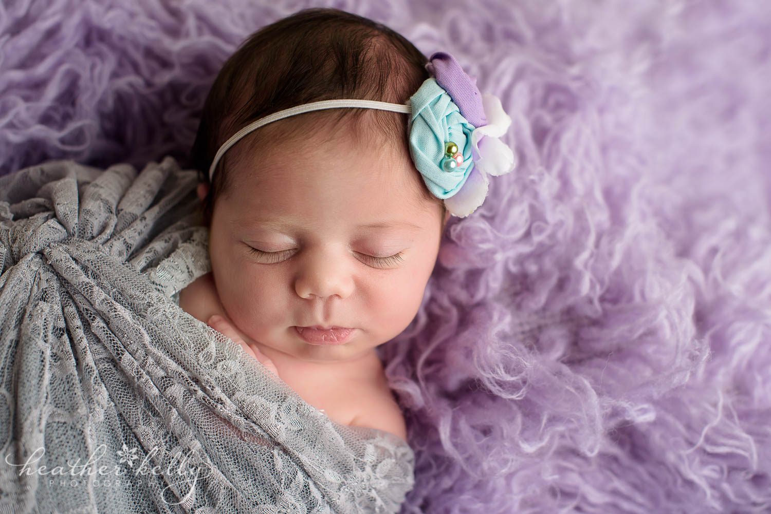 baby girl wrapped in gray lace on lavender flokati. newborn wrapping poses