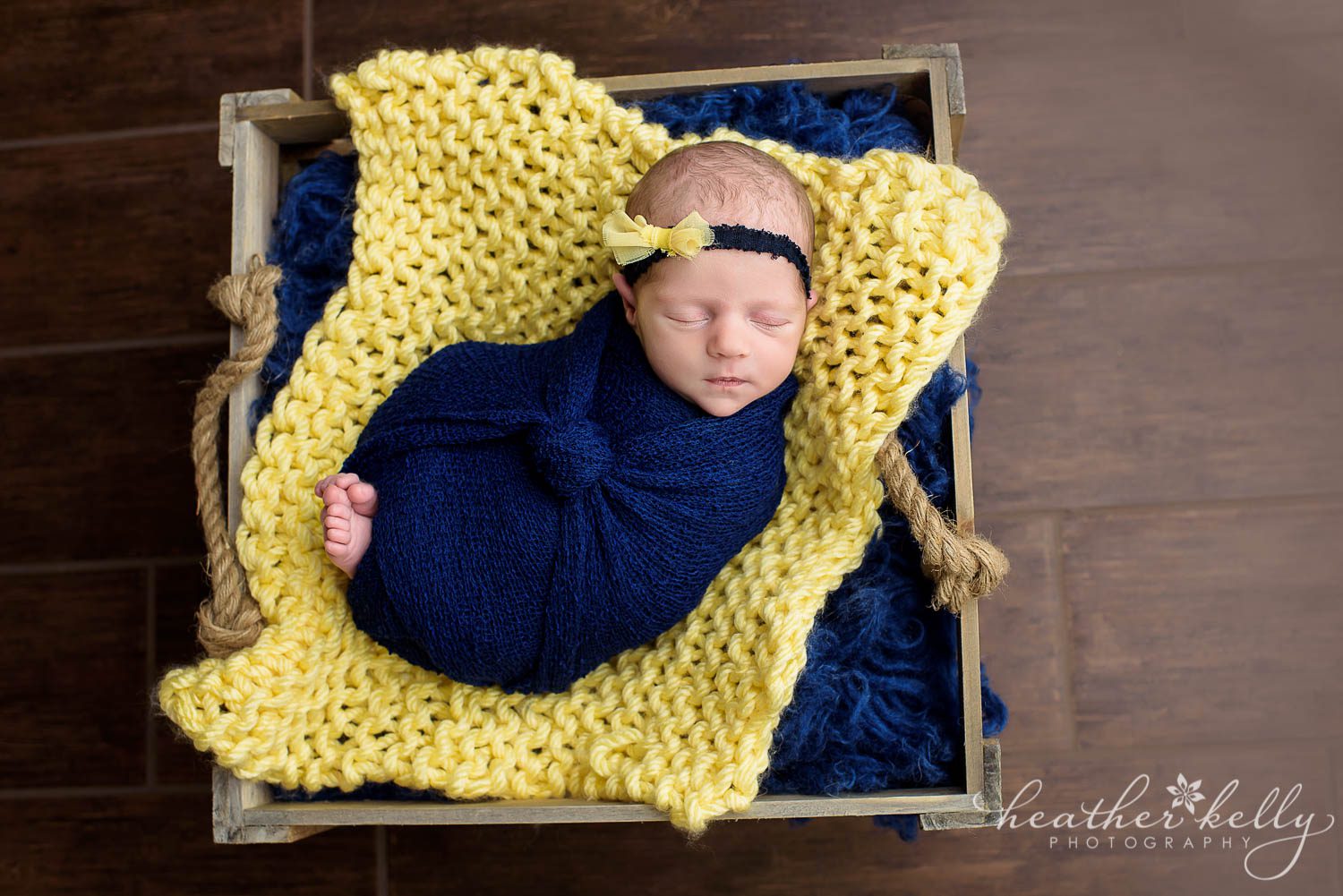 navy wrapped newborn girl in yellow crate. newborn wrapping poses