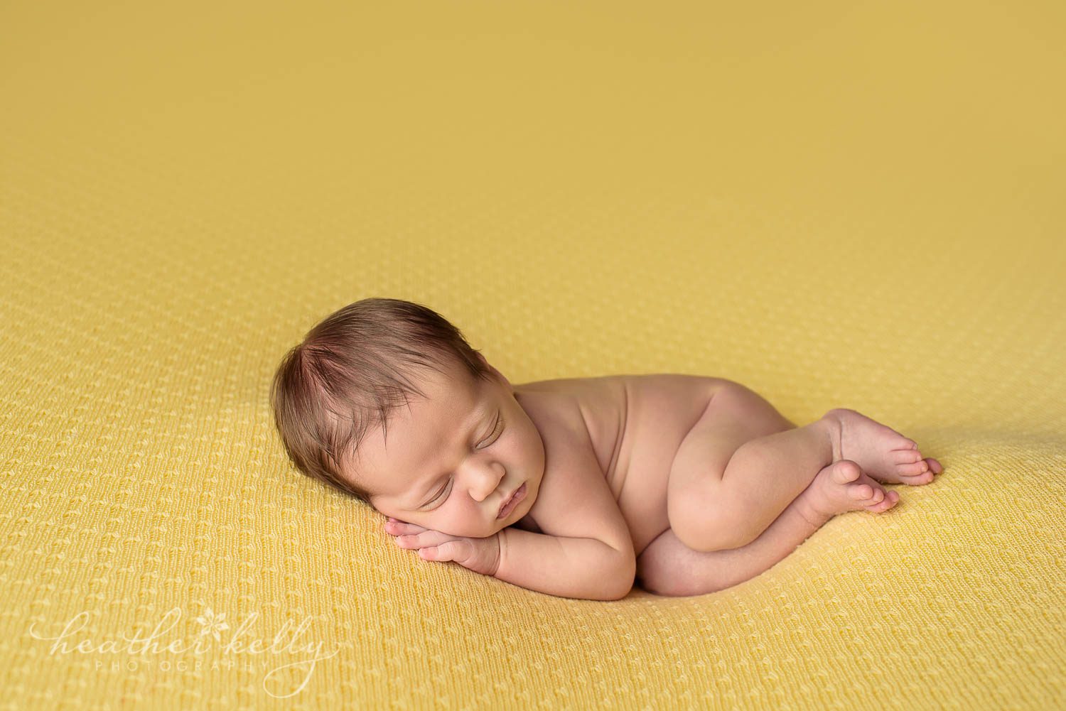 sleeping newborn boy naked on yellow