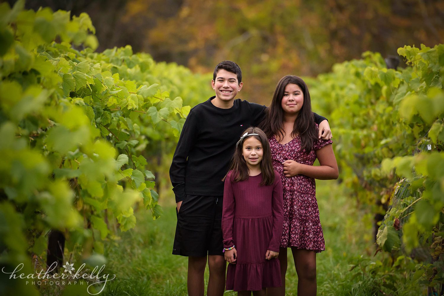 three siblings posing in between vines at Aquila's nest vineyard in Newtown CT 
