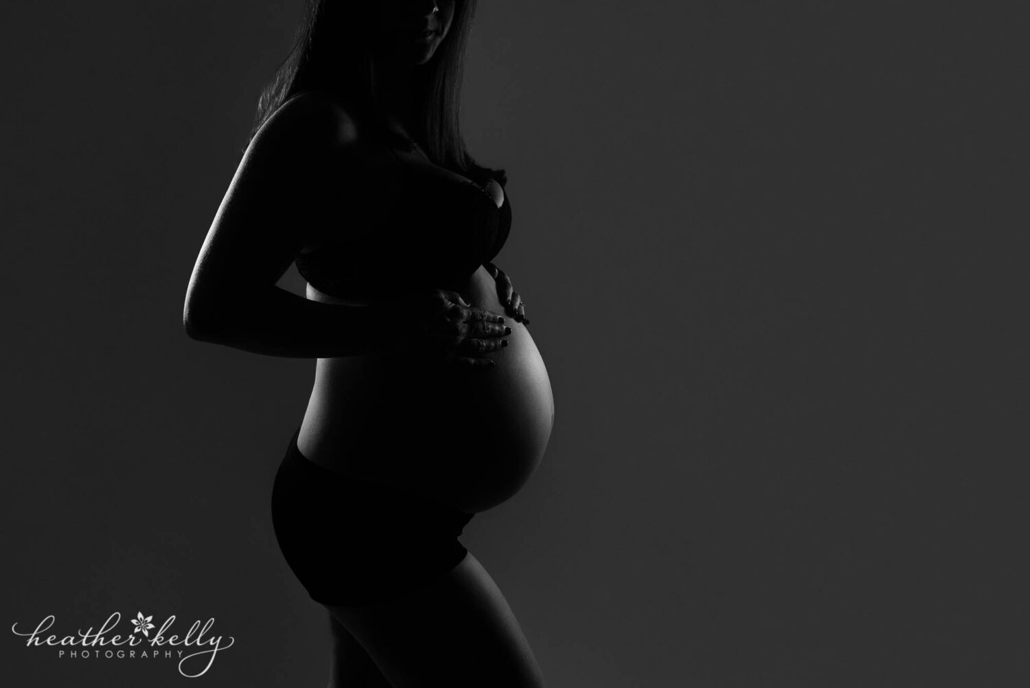 low key light maternity image of 35 week pregnant mom highlighting her belly and back. 

sandy hook maternity photography ct