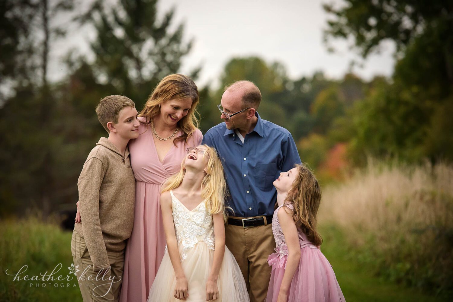 newtown area family photography. Family of 5 in a field all looking at each other lovingly. 