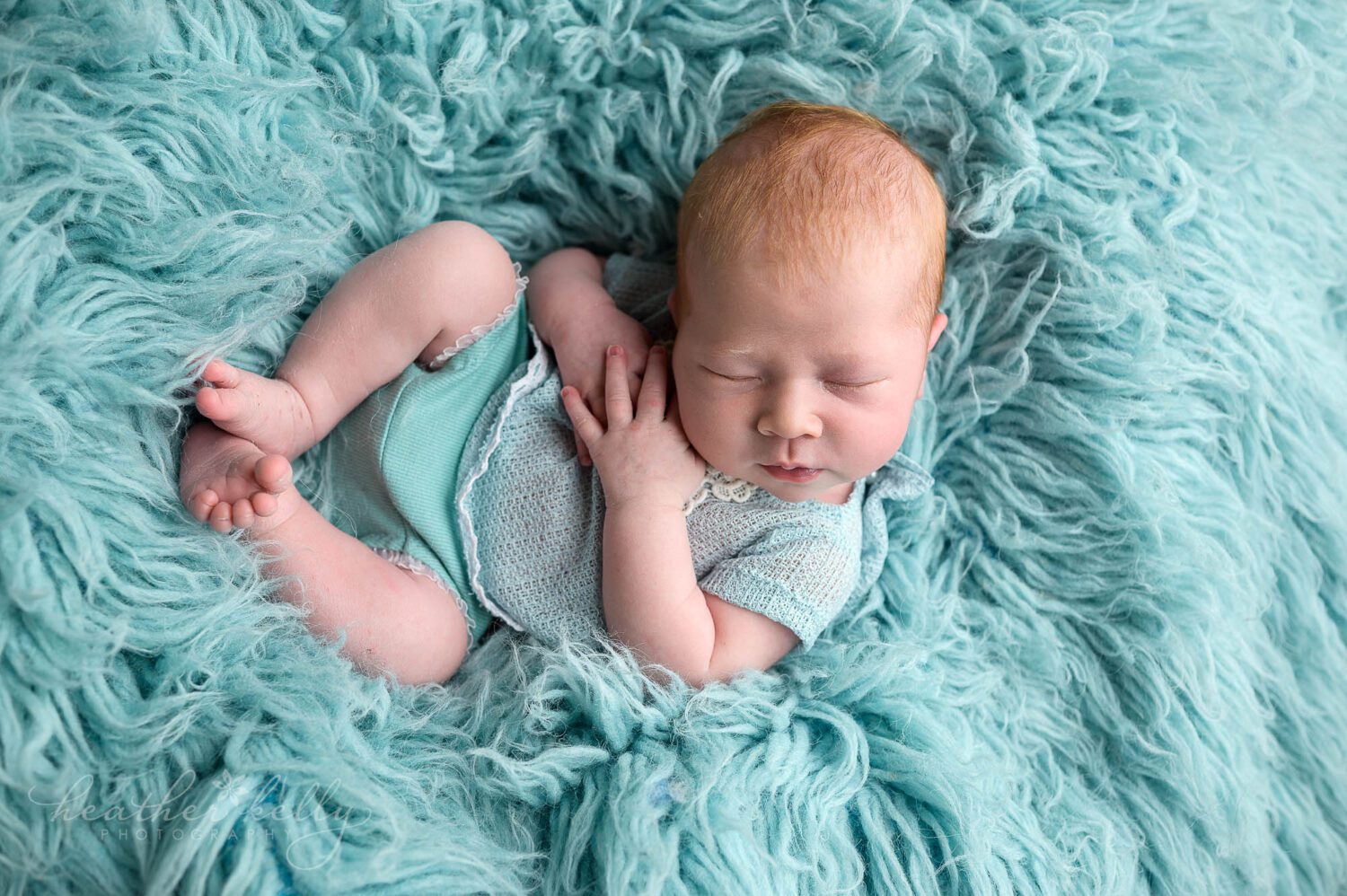 a professional newborn photography session of a baby girl with aqua rug. She is wearing an aqua outfit. 