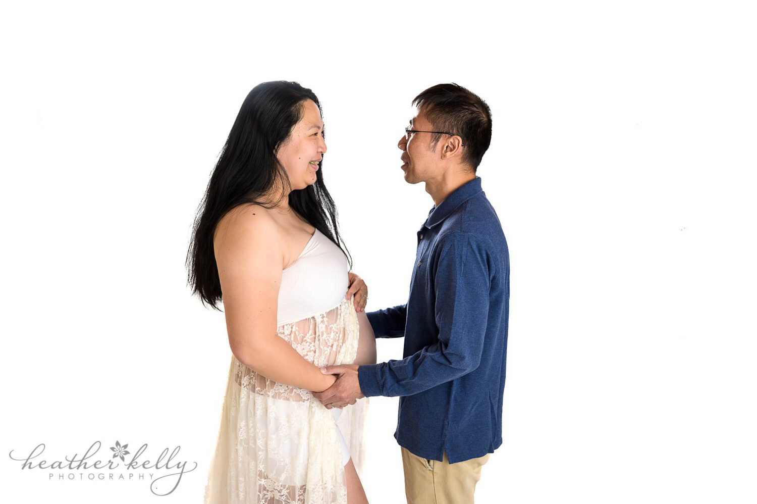 A high key white background. A maternity photography session. Mom to be a dad to be are looking into each other's eyes. Danbury maternity photographer